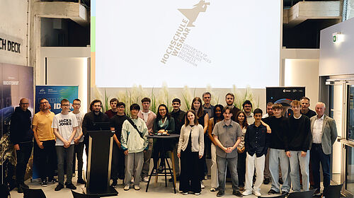 Schülerinnen und Schüler aus Schwerin und Lübeck stehen gemeinsam mit Vertreterinnen und Vertretern der Hochschule Wismar und der Jury beim Finale des Ideenwettbewerbs im InnovationPort Wismar.