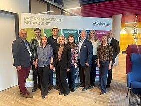Projektmeeting des DigiTechPort2030-Konsortiums bei acquinet Mitglieder des internationalen DigiTechPort2030-Konsortiums stehen gemeinsam in den Räumlichkeiten von acquinet vor einer Präsentationswand zum Thema Datenmanagement und Projektarbeit.