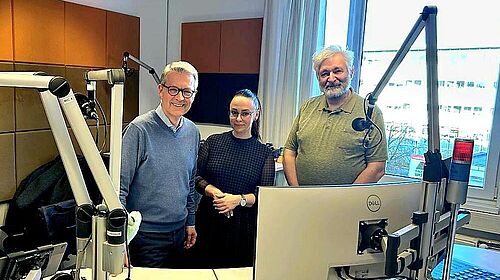 Drei Personen stehen in einem Radiostudio mit Mikrofonen und Mischpult und präsentieren das Projekt EUComplianceM4UA bei Radio LOHRO.