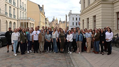 A large group is posing for a group photo in Schwerin city centre.