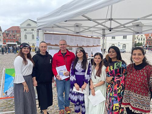 Frank Junge is standing under a pavilion on Wismar’s market square with Dr Anna Fomenko and five students.