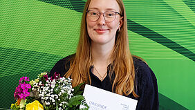 Lara Baumbach honoured for her Bachelor’s thesis Lara Baumbach holds her certificate and a bouquet of flowers after receiving an award for her bachelor’s thesis.