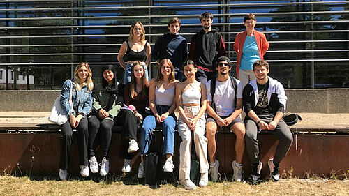 A group picture in front of the glass facade of the library of the Wismar University of Applied Sciences, students of the Erasmus+ program and their supervisor Mrs. Reese.