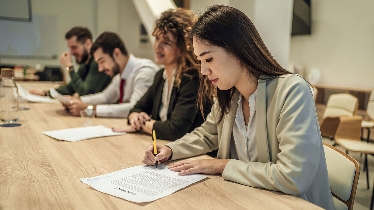 Introduction_Image Studiengang Wirtschaftsrecht Drei Personen sitzen an einem Tisch und sitzen über Vertragsentwürfen