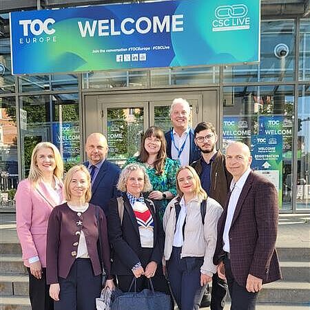 Mehrere Projektpartner des DigiTechPort2030-Konsortiums stehen vor dem Eingang der TOC Europe 2026 in Hamburg. Über ihnen befindet sich ein großes Willkommensschild der Fachmesse.