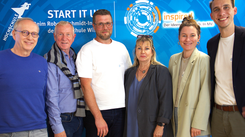 Sechs Jurymitglieder stehen nebeneinander vor einem blauen Hintergrund mit dem Logo des Robert-Schmidt-Instituts und des INSPIRED-Wettbewerbs. Alle blicken in die Kamera und lächeln.