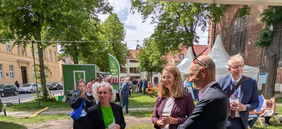 Personengruppe auf dem Veranstaltungsgelände vor der Kirche. Laima Gerlitz im Gespräch mit der Ministerin Bettina Martin und Prof. Junghanß von der Universitätsmedizin Rostock.