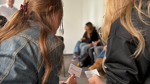 Demokratische Entscheidungsprozesse im Rollenspiel Zwei Personen halten Karten mit Rollenbeschreibungen während eines Workshops zur Demokratiebildung.