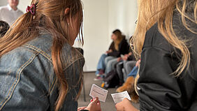 Demokratische Entscheidungsprozesse im Rollenspiel Zwei Personen halten Karten mit Rollenbeschreibungen während eines Workshops zur Demokratiebildung.