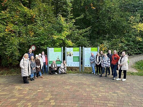 International project partners of the Interreg project Back2Woods stand in front of information boards in the forest area during an excursion in the Heilwald Heringsdorf.
