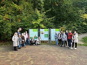 International project partners of the Interreg project Back2Woods stand in front of information boards in the forest area during an excursion in the Heilwald Heringsdorf.
